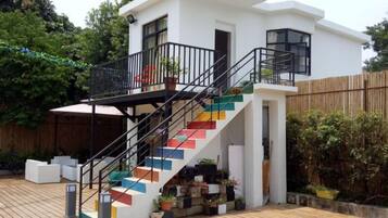 A modern two-story house with a staircase featuring colorful steps, a balcony, and a wooden deck.
