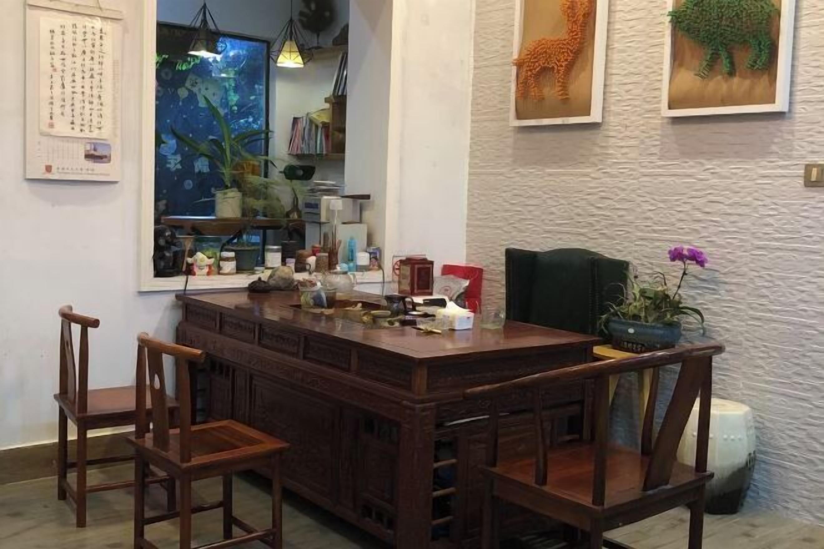 A wooden dining table with chairs, a calendar, a bookshelf, and decorative items.