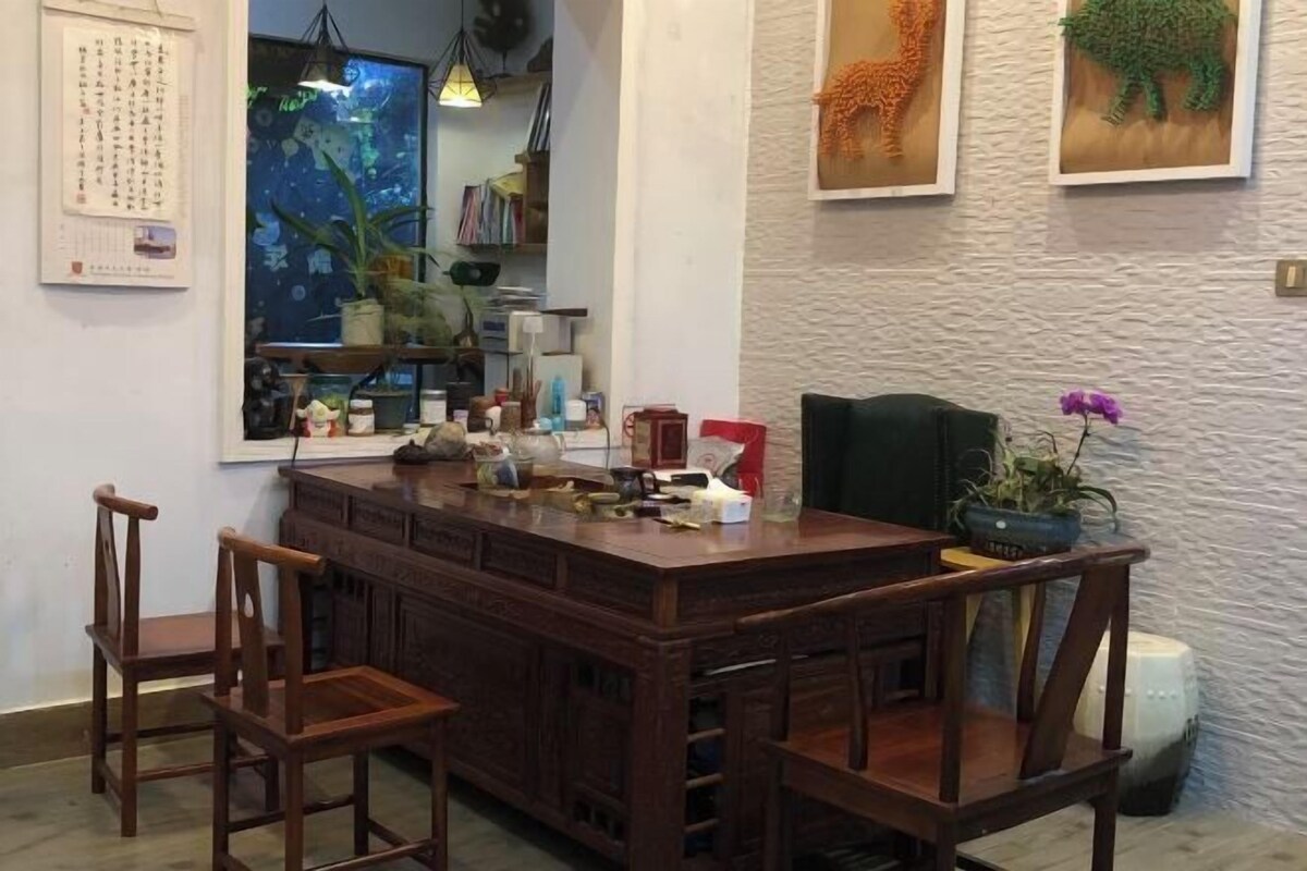 Una mesa de madera con sillas, un calendario, una estantería y elementos decorativos.