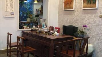 A wooden dining table with chairs, a calendar, a bookshelf, and decorative items.
