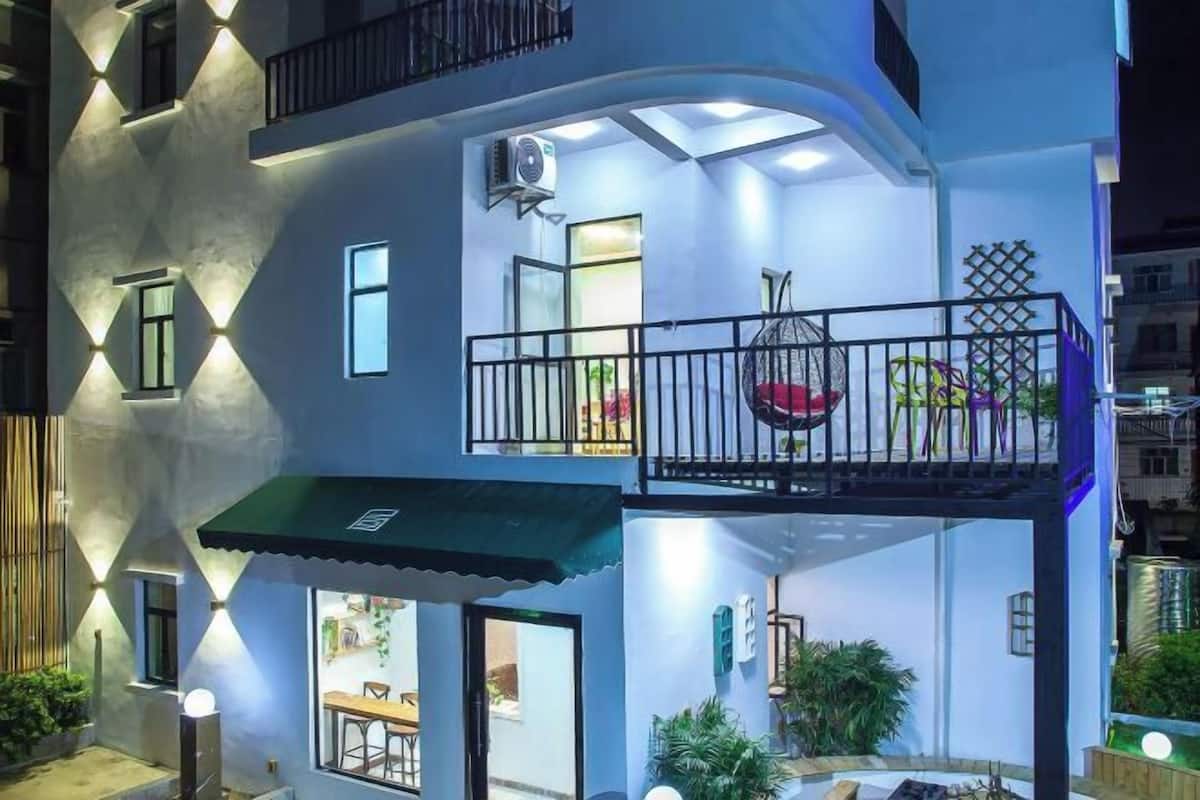 A multi-story building with a balcony, outdoor seating, and a green awning.