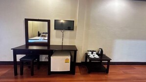 A room with a wooden desk, a small refrigerator, a television mounted on the wall, and a small table with cups and a kettle. - Y Not Lao Villa (Luang Prabang)