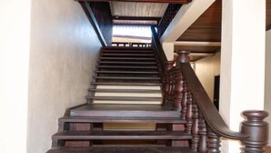 A wooden staircase with a handrail and a view of the outside through a window at the top. - Y Not Lao Villa (Luang Prabang)