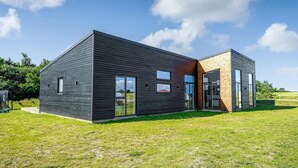 A modern two-story building with a dark exterior, large windows, and a grassy lawn. - Beautiful home in Børkop with sauna (Børkop)