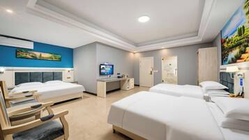 A hotel room with two beds, a desk, a chair, and a television.