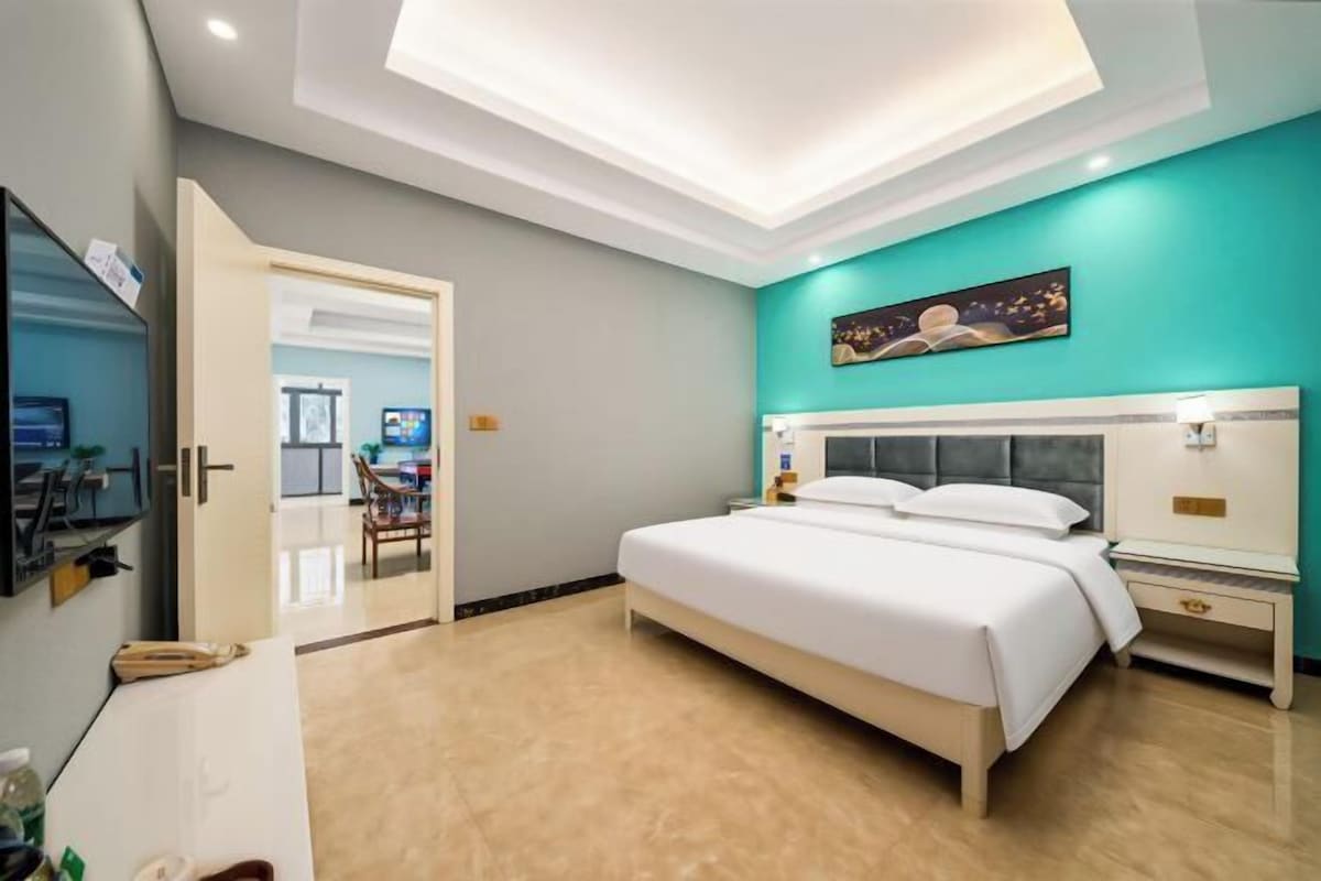 Una habitación de hotel con cama, mesitas de noche, televisor y escritorio.