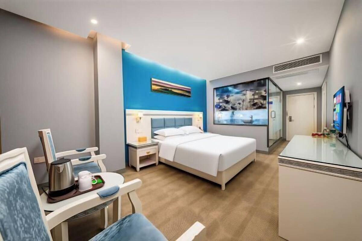 Una habitación de hotel con cama, mesita de noche, silla, escritorio y televisión.