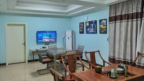 A dining area with a wooden table and chairs, a television on the wall, and a door to the left. - Guangdu Hotel, Suixi (Cenxi)