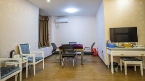 Una habitación con una mesa de comedor, sillas, un televisor y un escritorio.