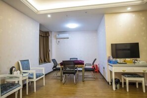 A room with a dining table, chairs, a TV, and a desk.
