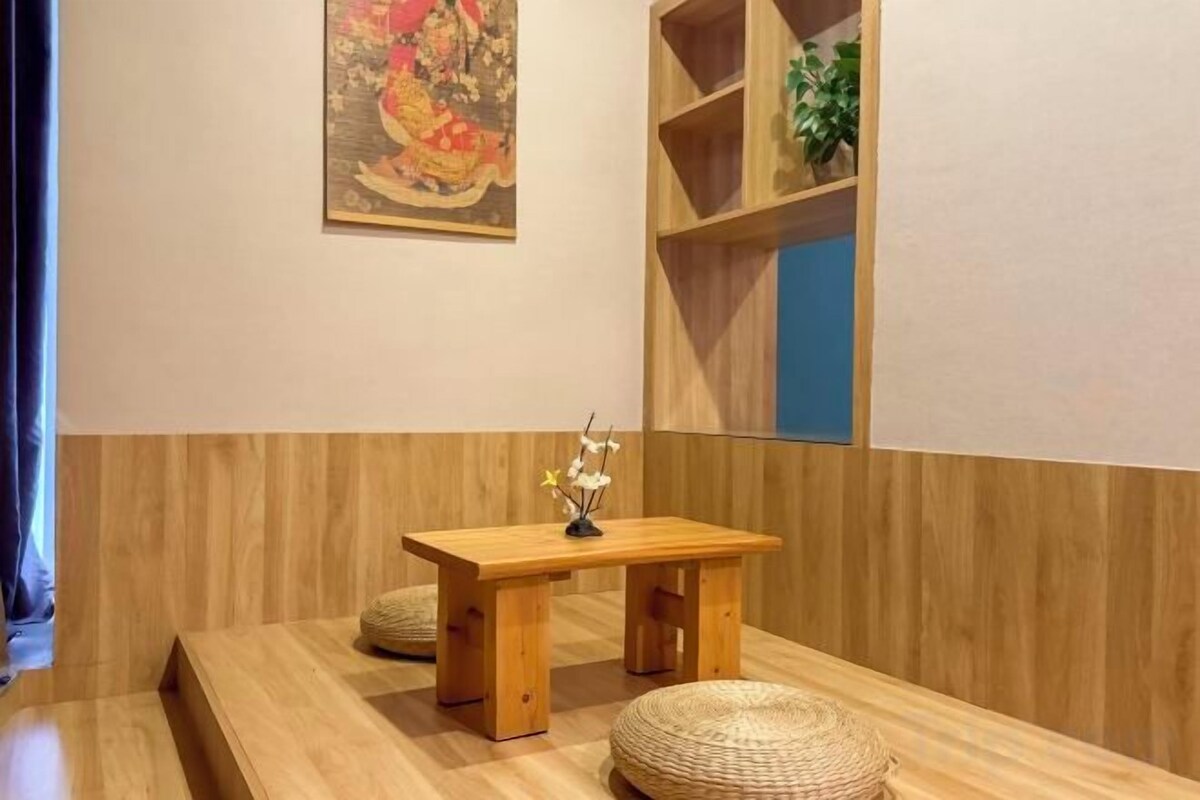 Un banco de madera con una pequeña mesa y un taburete tejido en una habitación con paneles de madera y un cuadro en la pared.