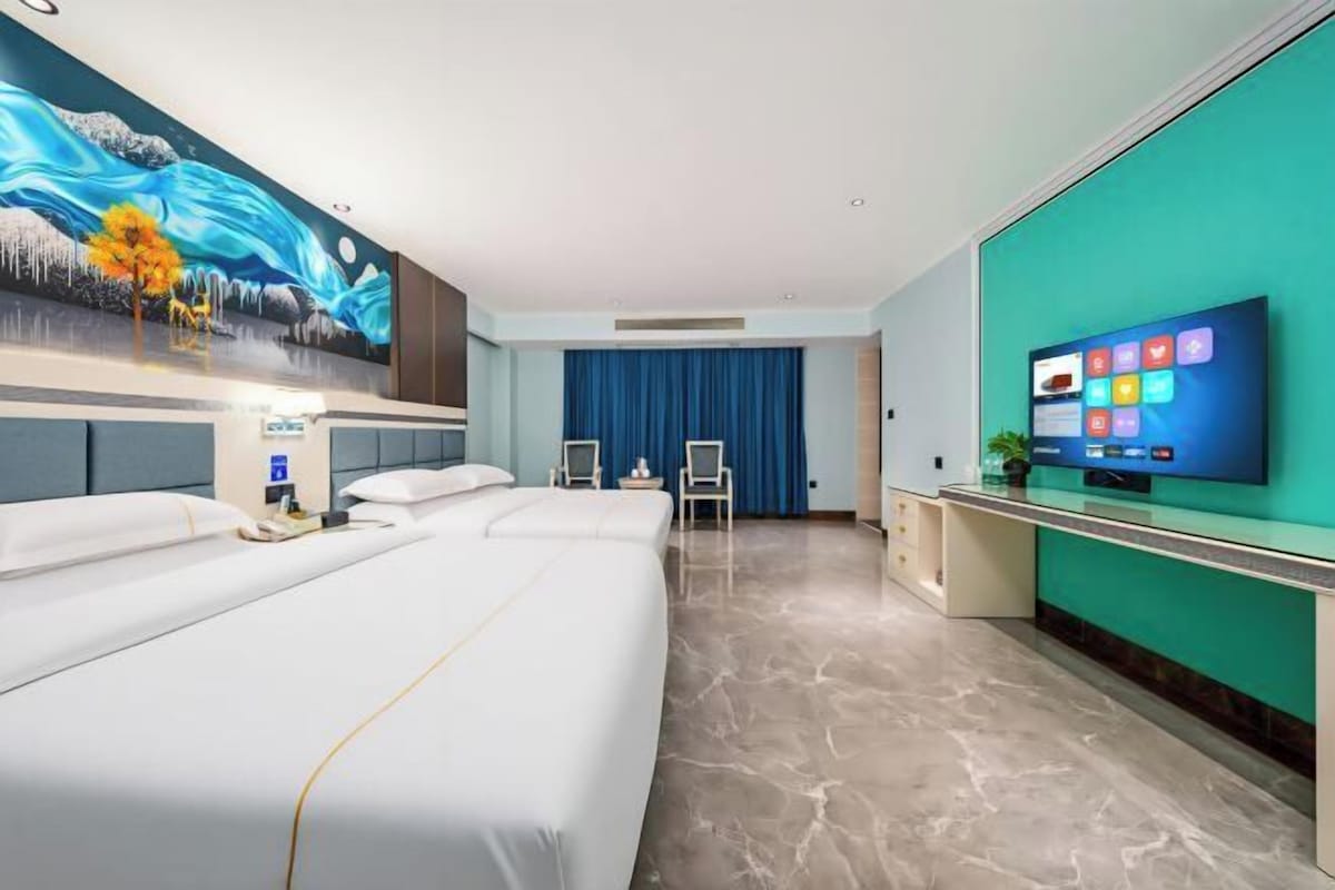 Una habitación de hotel con una cama grande, un escritorio, un televisor y un cuadro en la pared.