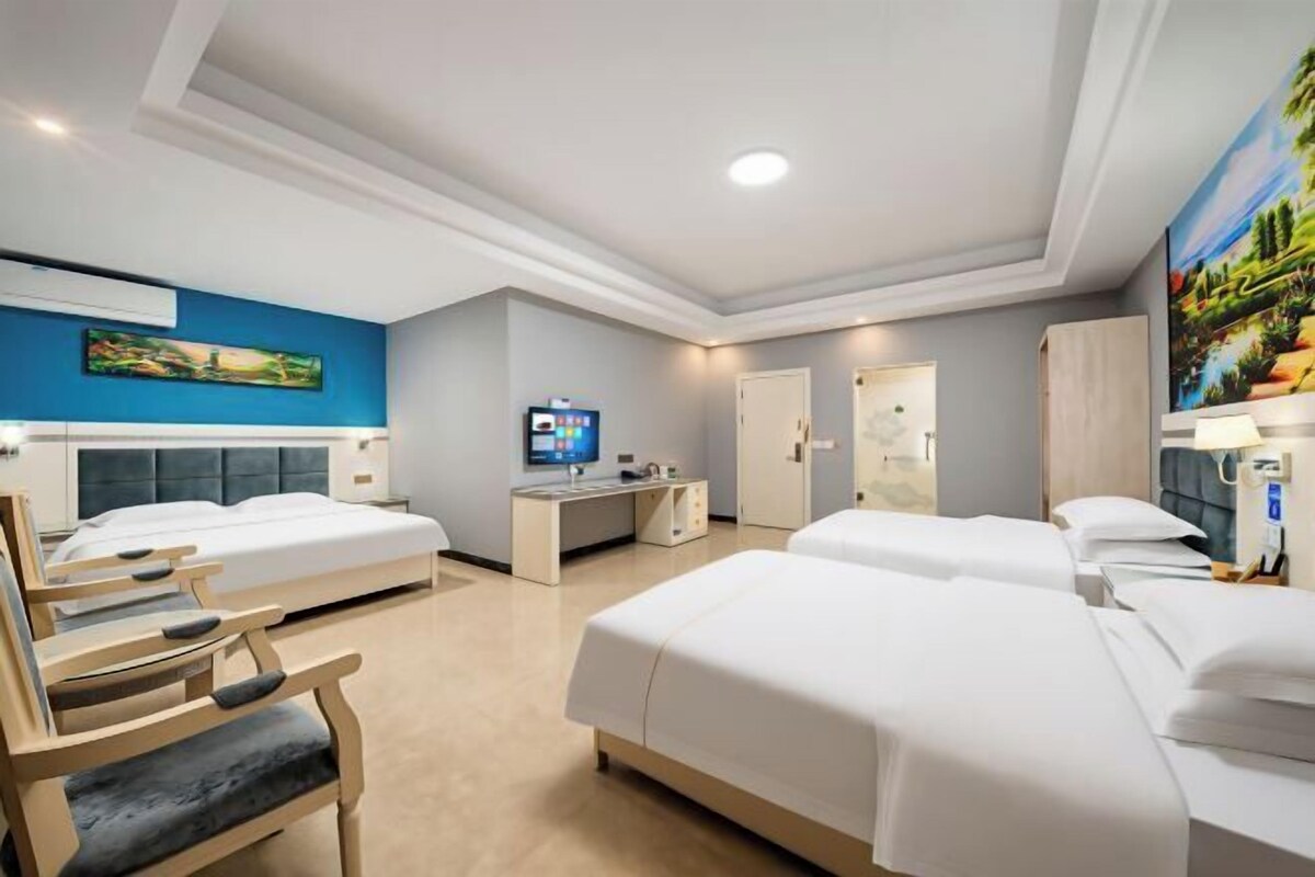 Habitación de hotel con dos camas, un escritorio, una silla y un televisor.