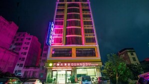 Un hotel de varios pisos con un cartel llamativo que dice “GUANGDU” y una señal de neón sobre la entrada.