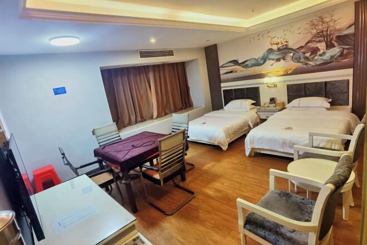 A hotel room with two beds, a desk, a chair, and a mural on the wall.