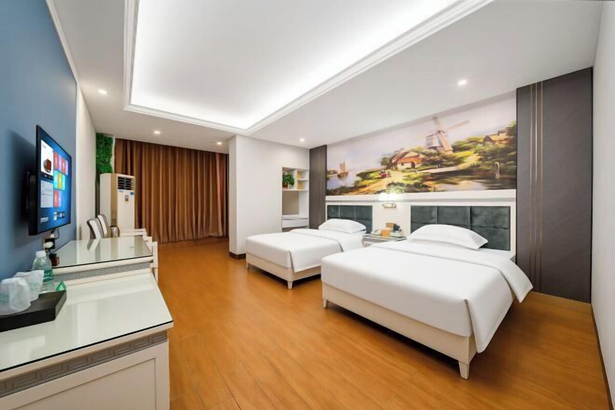 Habitación de hotel con cama, escritorio, televisor y un cuadro en la pared.