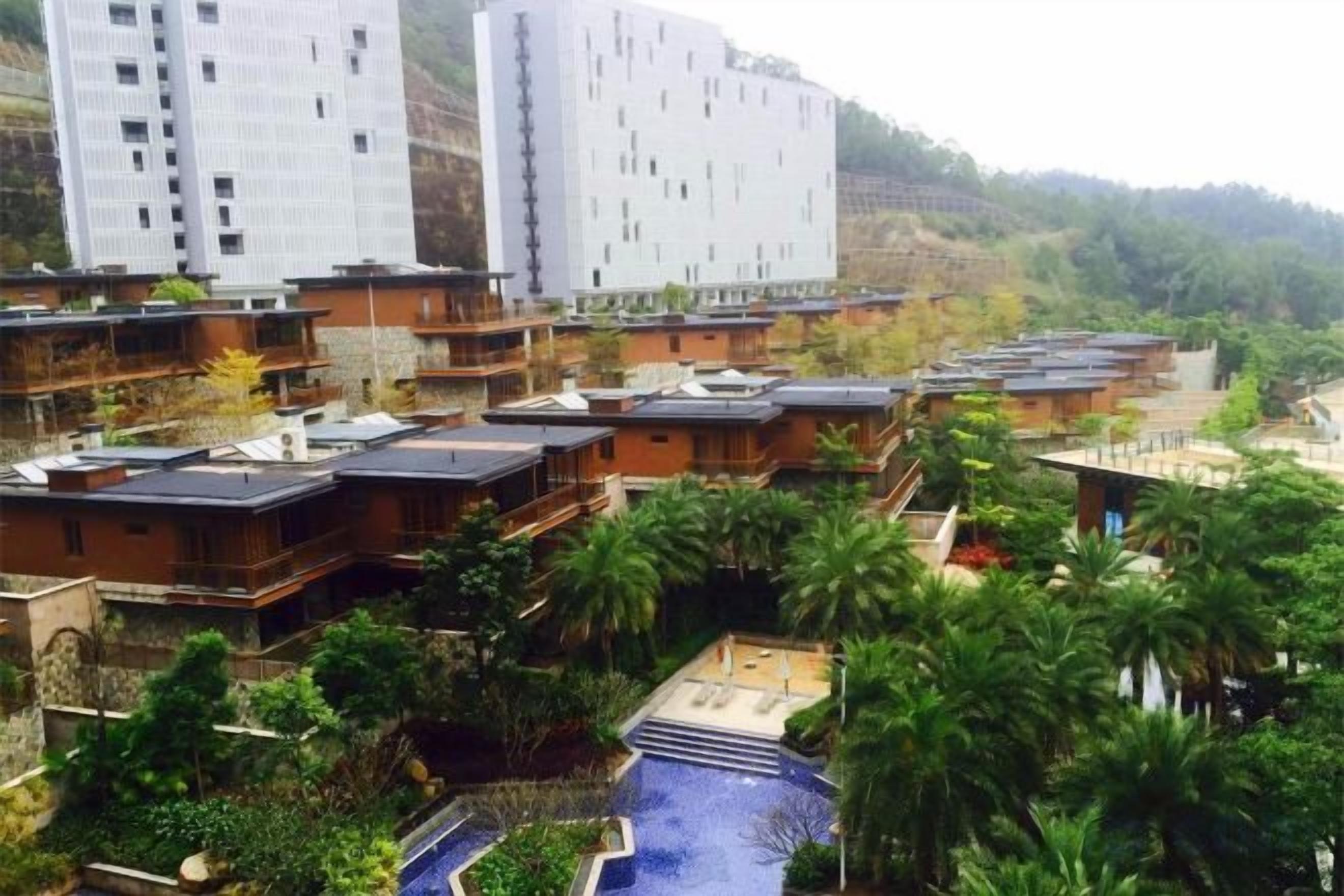 A residential area with multiple two-story buildings, a swimming pool, and lush greenery.