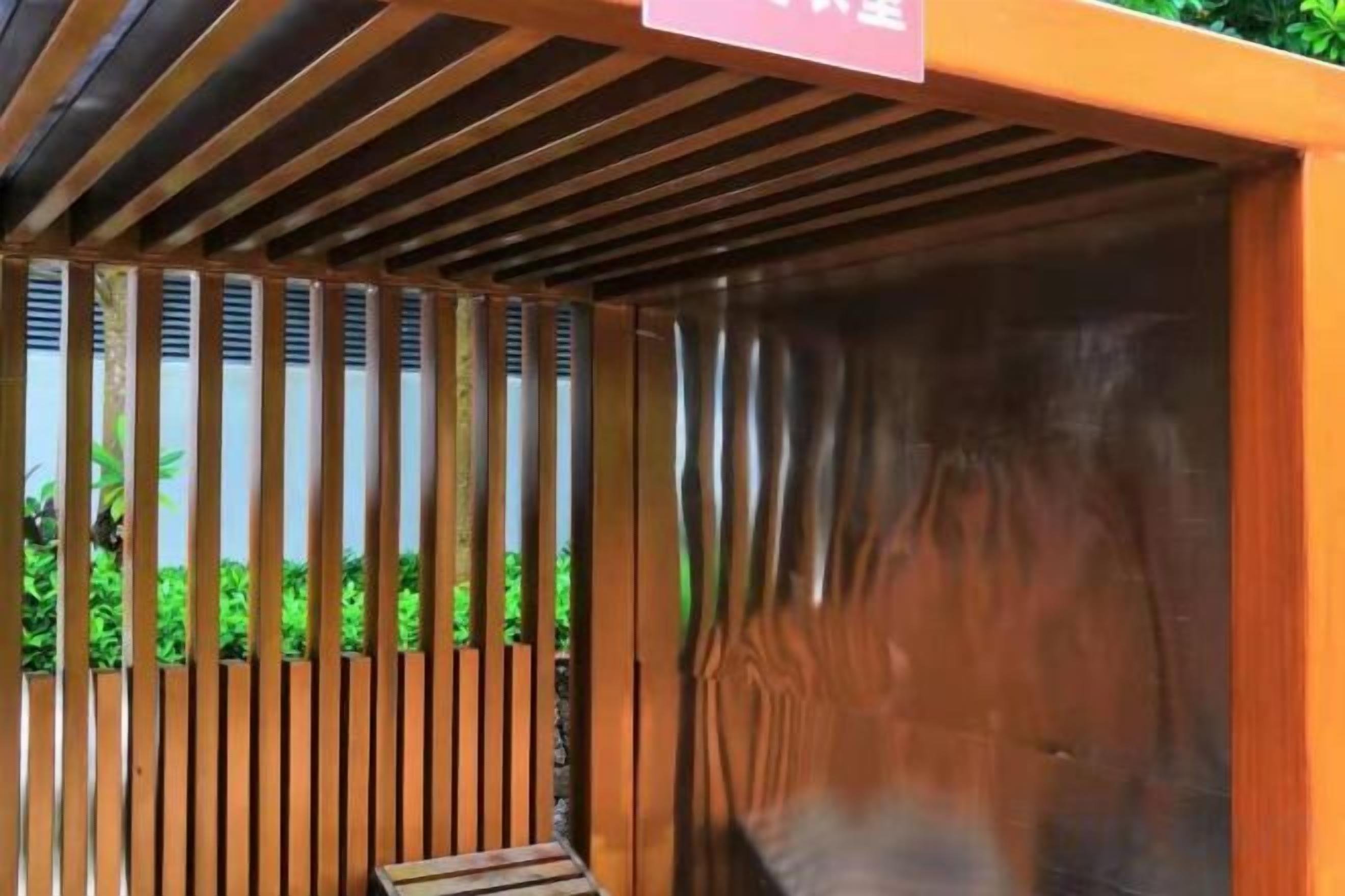 Una estructura de madera con listones verticales y una superficie metálica, posiblemente parte del revestimiento exterior de un edificio.