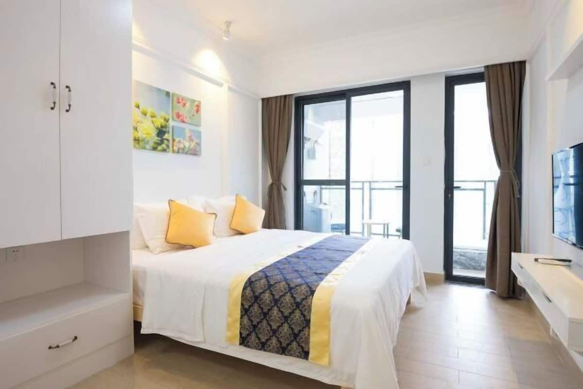 Habitación de hotel con cama, televisor, escritorio y balcón.
