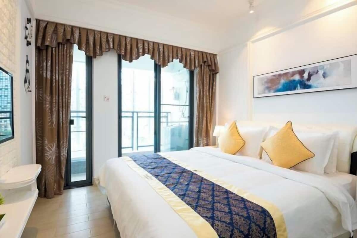 Habitación de hotel con una cama grande, baño y balcón con cortinas.