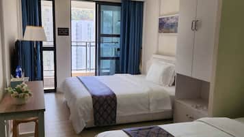 A hotel room with two beds, a desk, a chair, and a view of the outside.