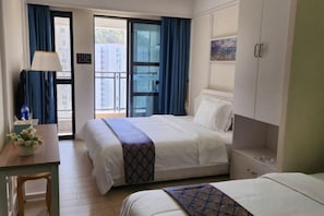 Ein Hotelzimmer mit zwei Betten, einem Schreibtisch, einem Stuhl und Blick ins Freie.