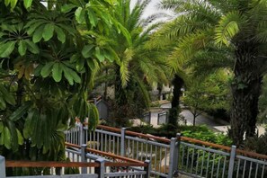 Una escalera con barandales de metal y vistas a un exuberante jardín con diferentes árboles y arbustos.