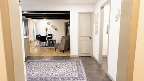Un pasillo que conduce a un comedor con alfombra, una mesa con sillas y un sofá.