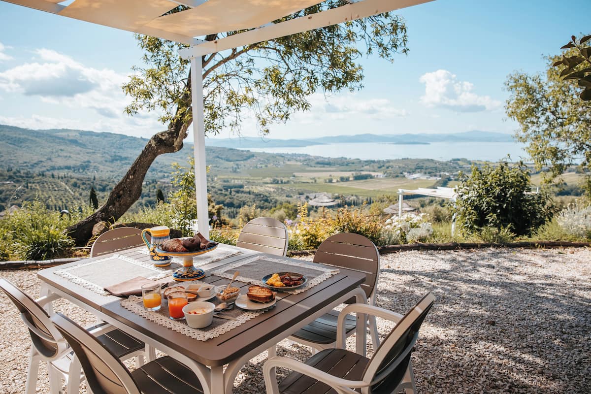 An outdoor dining area with a table set for breakfast, overlooking a scenic landscape.