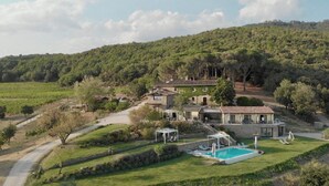 Eine Villa mit Schwimmbad, umgeben von üppiger Vegetation und Hügeln.