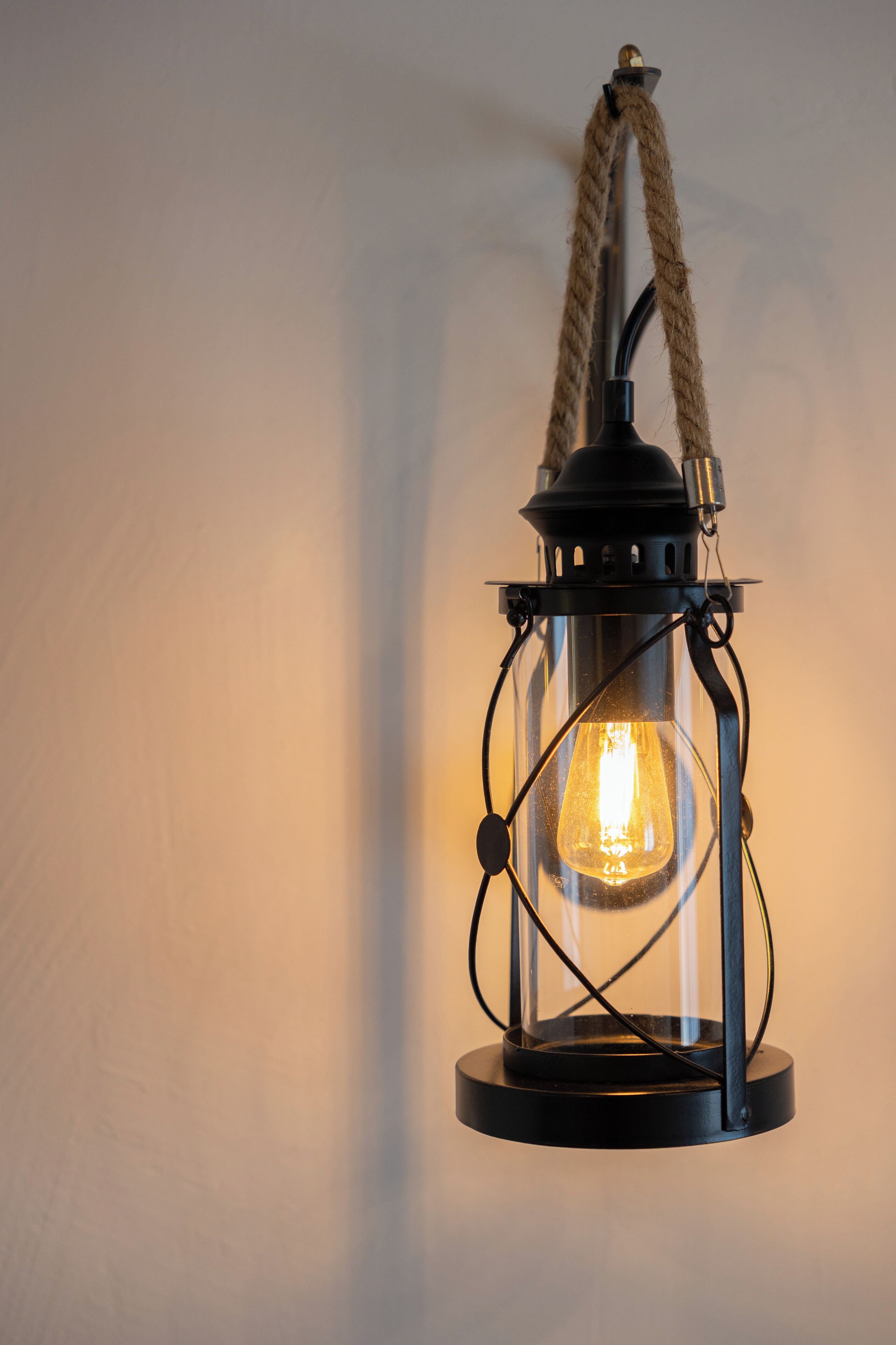 A black lantern with a rope handle and a visible light bulb.