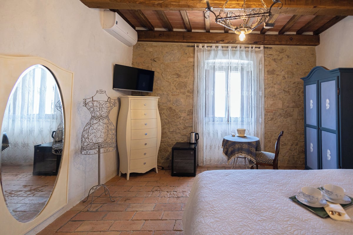 A bedroom with a bed, dresser, television, and a small table with cups and saucers.