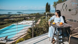 Eine Frau sitzt an einem Tisch mit Blick auf einen Swimmingpool und die entfernte Landschaft.