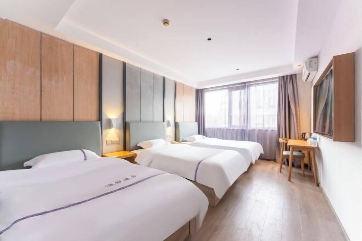 Habitación de hotel con dos camas, un escritorio y una ventana con cortinas.