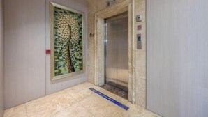 An elevator with a marble wall and a framed artwork above it. - Bojin Hotel (Cixi Zhouxiang Bus Station) (Cixi)