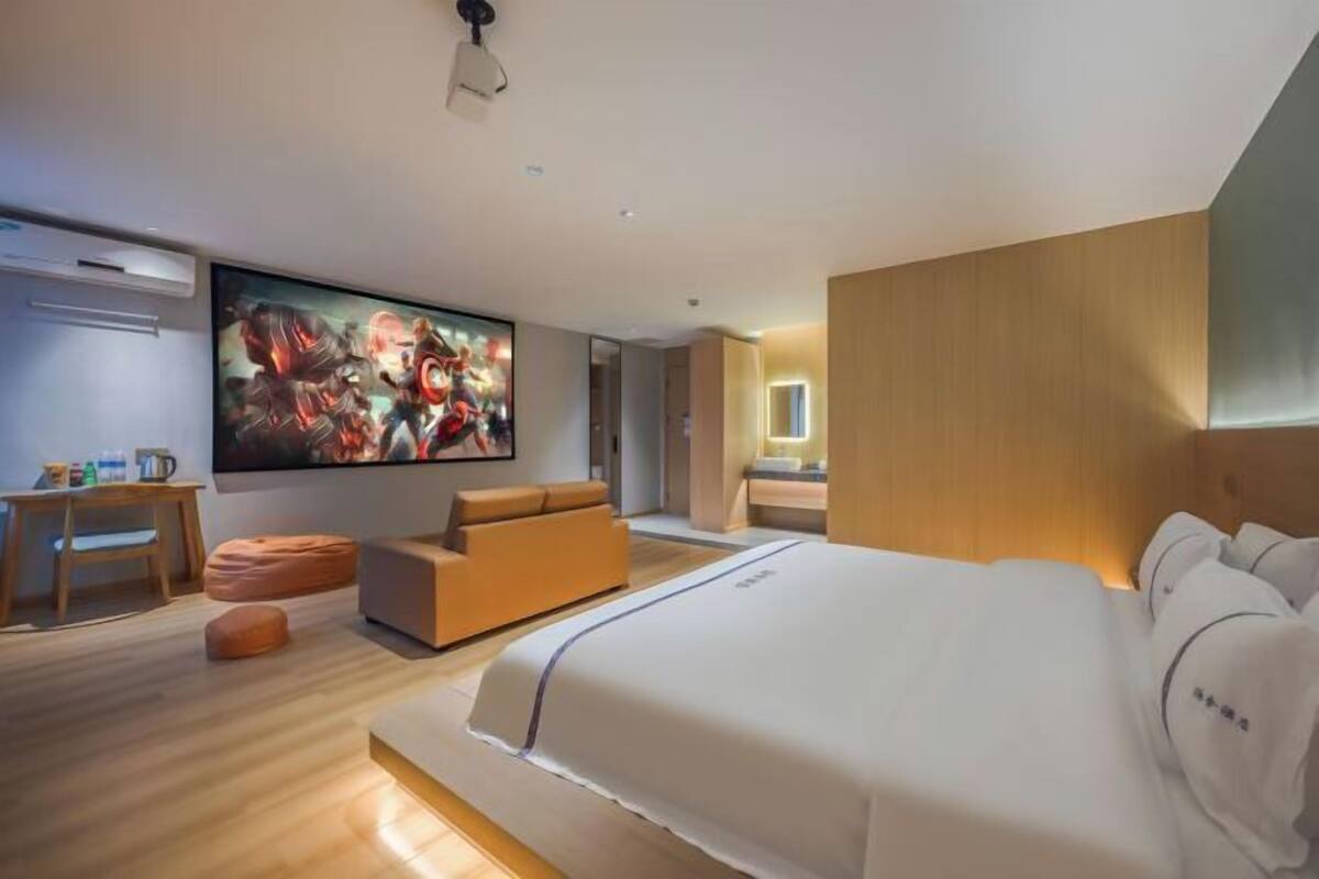 Una habitación de hotel moderna con una cama grande, un área de descanso, un televisor y un revestimiento de pared de madera.