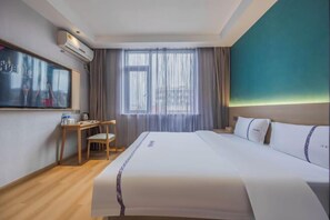 A hotel room with a large bed, a desk with a chair, a window with curtains, and a wall-mounted air conditioner. - Bojin Hotel (Cixi Zhouxiang Bus Station) (Cixi)