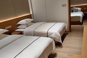 Two single beds with white bedding and dark trim, positioned against a wall with a wooden finish.