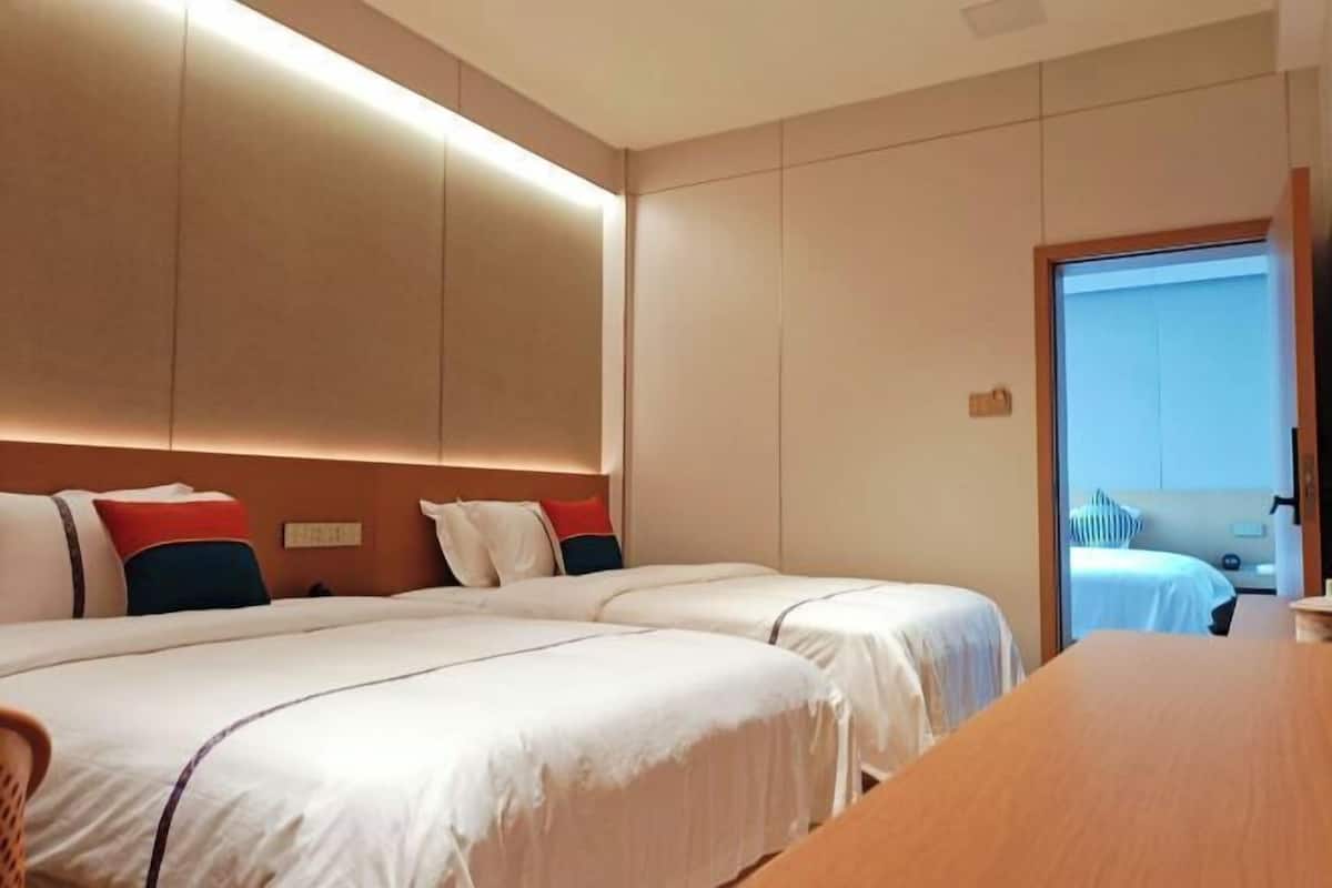 Ein Hotelzimmer mit zwei Betten, einem Holztisch und Blick auf den Balkon.