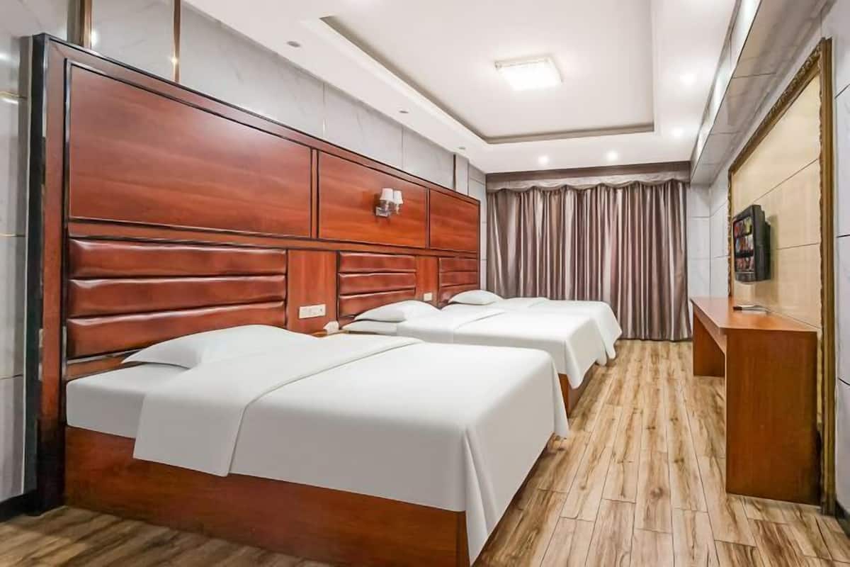 Ein Hotelzimmer mit zwei Betten, einem Holzkopfstück, einem kleinen Schreibtisch und einem Fernseher.