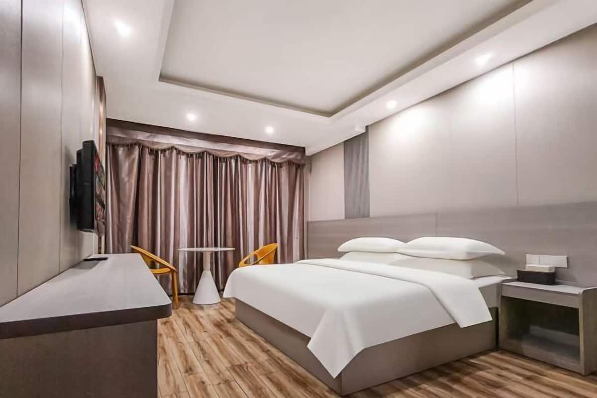 Ein modernes Hotelzimmer mit einem großen Bett, einem Schreibtisch, einem Stuhl und einem Fernseher.