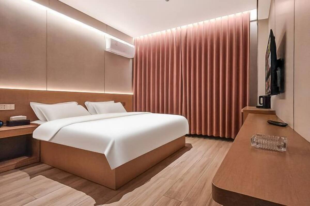 Ein modernes Hotelzimmer mit einem großen Bett, Nachttischen, einem Schreibtisch und einem Fernseher.