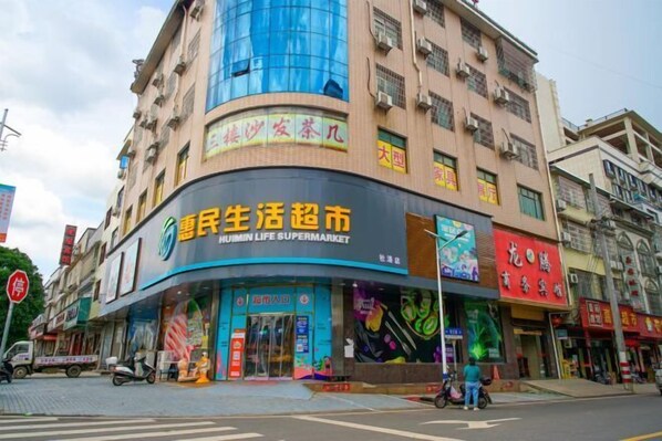 Located in an urban setting, this building features a curved facade with a Huimin Life Supermarket on the ground floor.