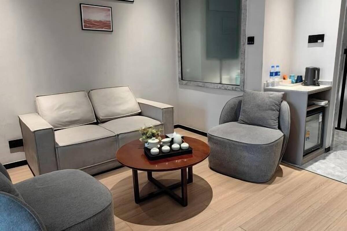 A modern living room with a grey sofa, a round coffee table, and a grey armchair.