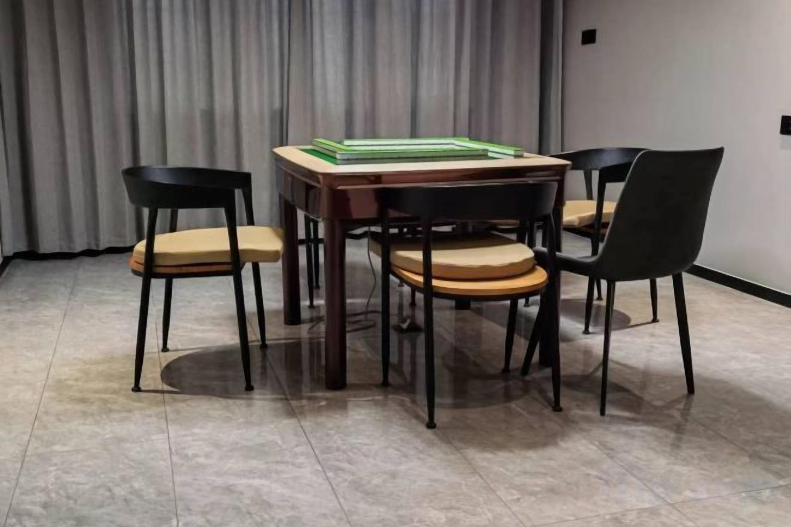 A conference room with a wooden table and four chairs, a grey curtain backdrop, and a tiled floor.