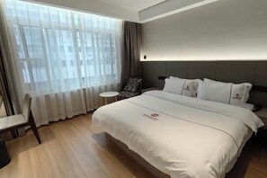 A hotel room with a large bed, a small table, a chair, and a window with curtains. - Ningbo Daxiebaodao Island Hotel (Ningbo)