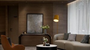 A modern living room with a curved sofa, a round coffee table, a floor lamp, and a framed artwork on the wall. - Ningbo Daxiebaodao Island Hotel (Ningbo)