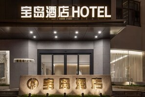 En hotelindgang med et skilt, der viser '宝岛酒店' og 'HOTEL' på engelsk.