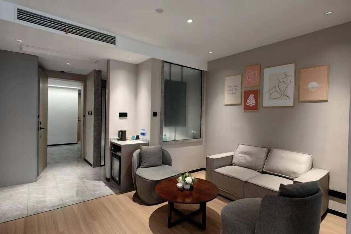 A modern hotel room with a sofa, armchairs, a coffee table, and artwork on the walls.