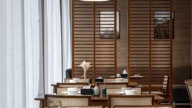 A restaurant with wooden slats, tables, chairs, and a hanging light fixture. - Ningbo Daxiebaodao Island Hotel (Ningbo)